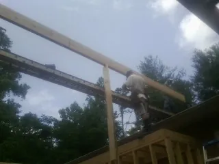 Carpenter setting a ridge beam over a new addition frame — Ice Dam Removal by Roofing Brothers in Traverse City