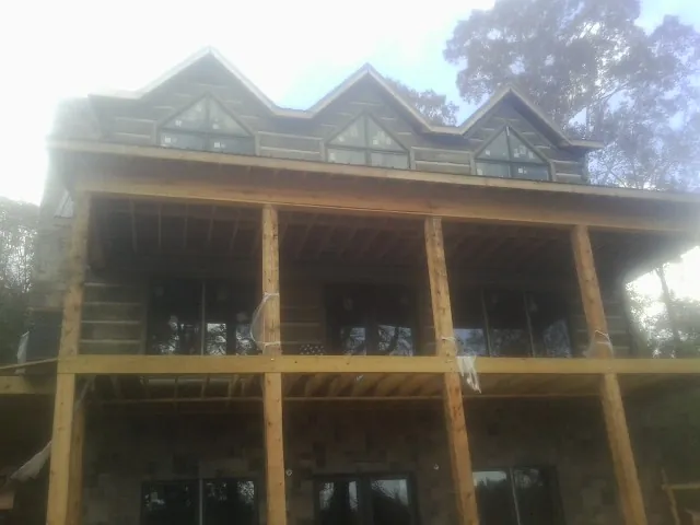 Dormers and porch framing on a large log home under construction — Roof Coating work by our crew in Traverse City